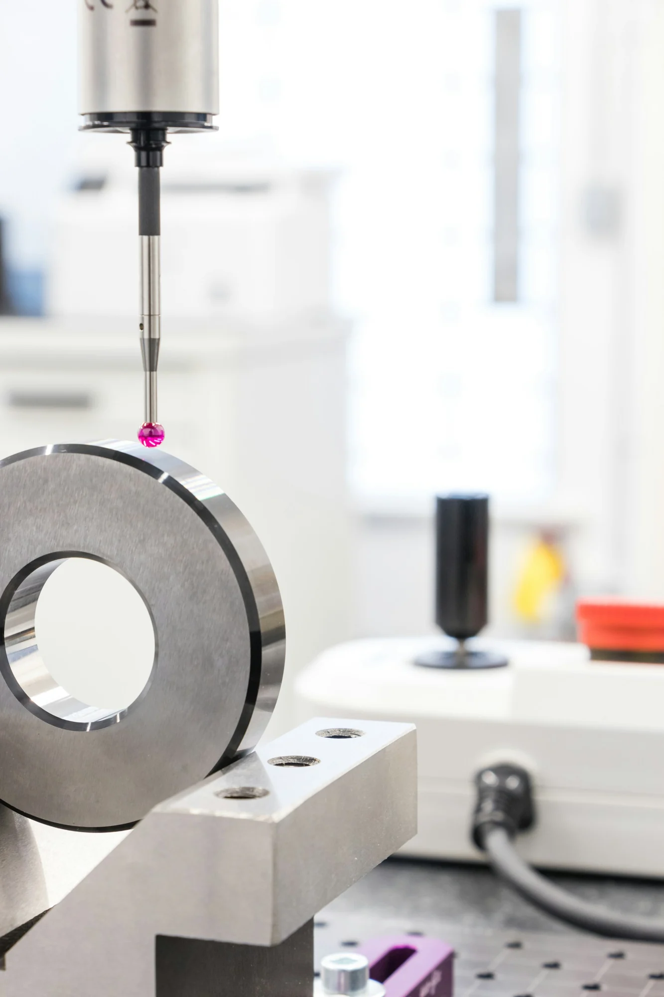 Ruby-tipped coordinate measurement probe beside a machined metal ring